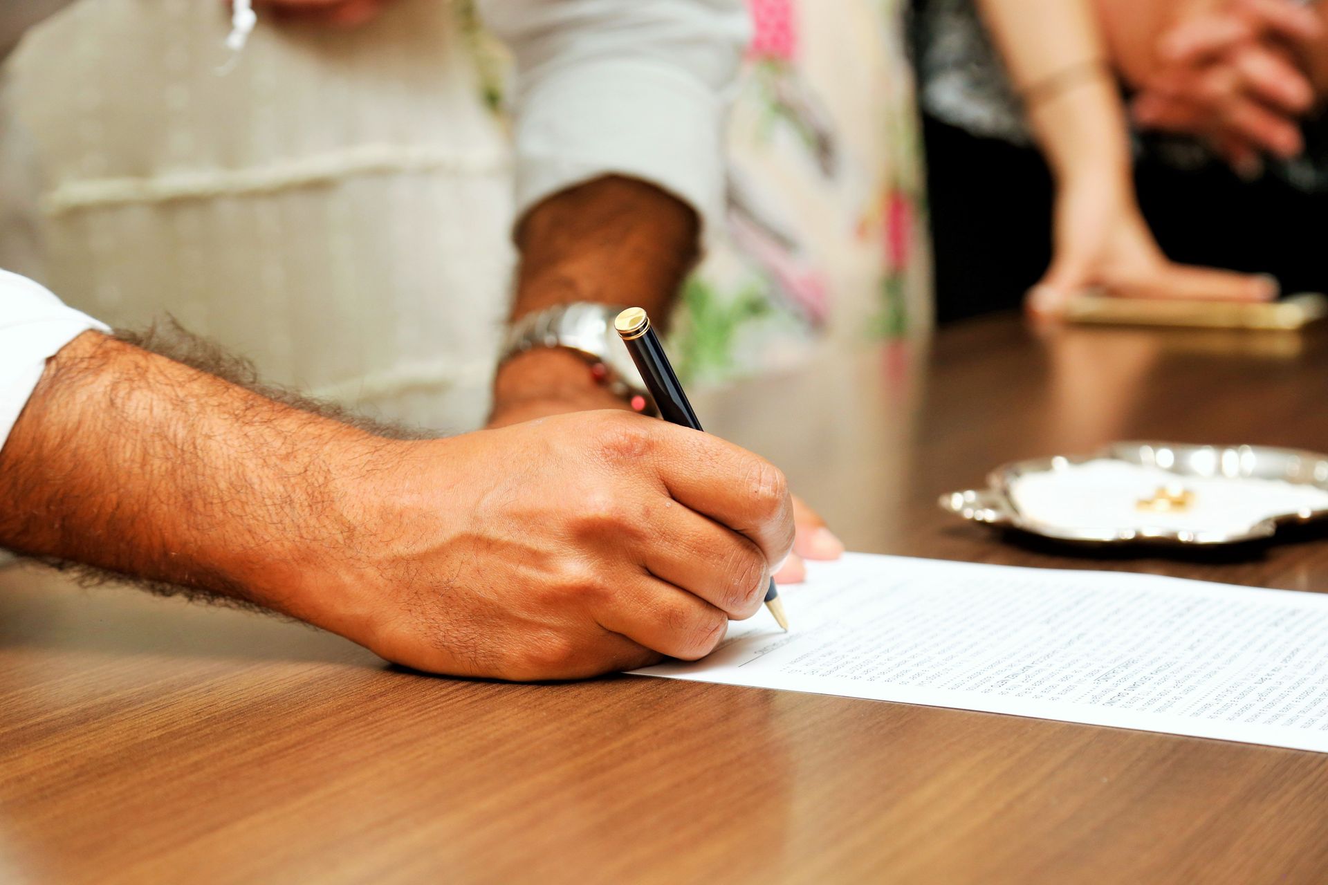 Close-up view of a person signing an important document with a pen on a wooden table.